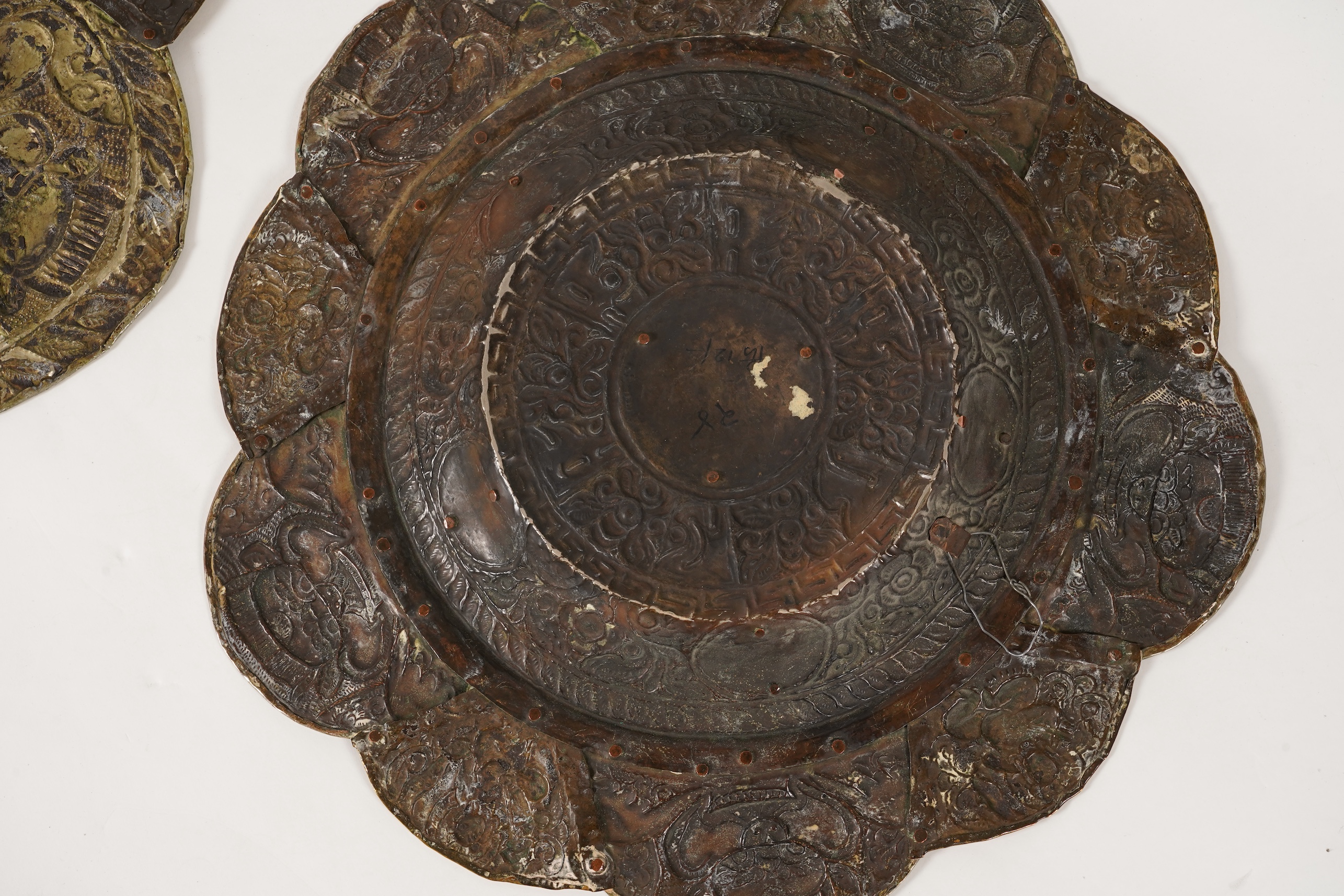 A graduated set of three Nepalese repoussé white metal and brass chargers, first half 20th century